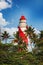 Thangassery Lighthouse on the cliff surrounded by palm trees and big sea waves on the Kollam beach. Kerala, India