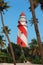 Thangassery Lighthouse on the cliff surrounded by palm trees and big sea waves on the Kollam beach. Kerala, India