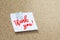 Thank you handwriting note on a wooden corkboard