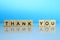 Thank you inscription made of wooden blocks on a blue background