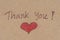Thank you message with red heart on brown paper.