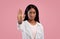 Thank you but no concept. Serious black woman making stop gesture on pink studio background