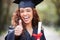 Thank you, portrait of female student with thumbs up and graduation day at college campus outdoors with certificate