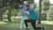 Thankful senior wife hugging husband tying shoelace on sneakers in spring summer park. Happy loving Caucasian woman