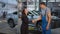 Thankful young woman smiling shaking hands with man in auto service station leaving in slow motion. Portrait of grateful