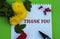 THANKS - words on a piece of paper with yellow flowers and a red pen on a green background. Information concept