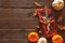 Thanksgiving or autumn harvest table setting with silverware, orange napkin, leaves and pumpkin border against a rustic wood backg