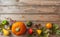 Thanksgiving flat lay with colorful pumpkins, fruits and fall leaves on rustic wooden background, copy space