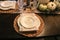 Thanksgiving formal table setting with pumpkin embossed dishes and natural fiber runner and napkins and woven place mats