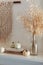 Thanksgiving home  decor - white wooden fireplace with wall macrame, cream and beige pumpkins, pine cones garland and rustic dry