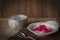 Thapthim krop, mock pomegranate seeds in coconut and syrup in the white bowl on the wood table there are spoon, and water bowl