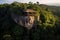 A thatched hut atop a unique rock formation amidst lush greenery, under the soft glow of sunrise