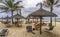 Thatched huts and beach chairs on tropical sandy beach