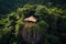 A thatched-roof hut perched on a mossy rock, surrounded by a dense, tropical forest. Isolation is conveyed by the image