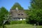 Thatched roof, thatched house with green garden, green trees and blue sky