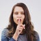 Thats all you need to do. Portrait of an attractive young woman posing with her finger on her lips against a grey