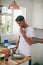 Thats a tasty sandwich. a handsome young man standing in his kitchen making a sandwich.