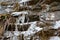 The thawing icicles with the falling water drop in the mountains