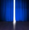 Theater blue curtain slightly open with bright light behind and wood stage or scene
