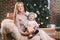 Theme Christmas holidays winter new year. A young stylish Caucasian mother holds her son in her arms for 1 year in a funny shirt