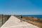 Theme of exploring island of Cyprus on foot. Man with a backpack is walks along the sea by coastal broadwalk in the city