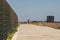 Theme of exploring island of Cyprus on foot. Man with a backpack is walks along the sea by coastal broadwalk in the city