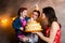 Theme family holiday childrens birthday and blowing out candles on large cake. young family of three people standing and holding 5