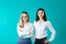 The theme is a female team. Portrait of two young caucasian business women posing in studio on a colored background. Teamwork two