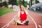 Theme healthy lifestyle, sports music. young Caucasian woman rests sitting treadmill running rubber stadium uses technodogy mobile