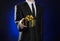 Theme holidays and gifts: a man in a black suit holds exclusive gift wrapped in a black box with gold ribbon and bow on a dark