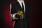 Theme holidays and gifts: a man in a black suit holds exclusive gift wrapped in a black box with gold ribbon and bow on a dark red