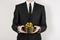 Theme holidays and gifts: a man in a black suit holds exclusive gift wrapped in a black box with gold ribbon and bow isolated on