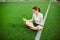 Theme sport and health. Beautiful young girl sitting resting on green grass, artificial turf stadium resting thirsty drink bottle