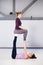 Theme sports health acrobatic yoga. A pair of two young Caucasian girls in the gym doing a base posture chair. Physical and