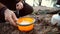 The theme of tourism is hiking and traveling in nature. Hands Caucasian man pours dry dried fast food porridge in a plate for