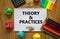 Theory and practice symbol. White note, words `Theory and practice` on beautiful wooden table, colored paper, colored pencils,