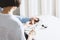 The therapist in blue shirt with a classic tonometer measuring blood pressure of an woman in home room on white table, soft focus