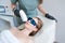 Therapist cosmetologist undergoes laser treatment on face young woman in beauty