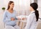 Therapist Giving Pregnant Woman Prescribed Medicines Sitting In Office