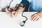 The therapist male hands in blue shirt with a classic tonometer measuring blood pressure of a man in home room on white table