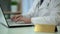 Therapist in uniform typing medical info on laptop, blank nameplate on table