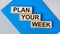 There is a blue notebook on a light gray background. Above are three wooden blocks with the words PLAN YOUR WEEK