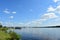 There is a boat on the river. River port. Bridge. Forest. Nature. Sunny weather. The sky, clouds scatter