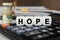 There are cubes on the calculator that say - HOPE. Nearby out of focus - dollars, notebook and pen