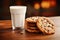 There is a glass of fresh milk and chocolate cookies on the table. Close-up