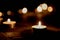 There are many burning candles with a small depth of field.Lots of candle lights glowing on a dark background on