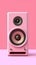 There is pink speaker sitting on top of purple background. The speaker appears to be small and has two speakers facing