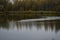 There is a pond in the autumn forest. Fallen leaves cover the ground with a multicolored