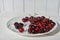 There's a bunch of cherries in the dish with space to copy. Close-up of a plate of ripe cherries in a white plate on