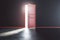 There is always a way out concept with sunlight coming through red open door into dark room